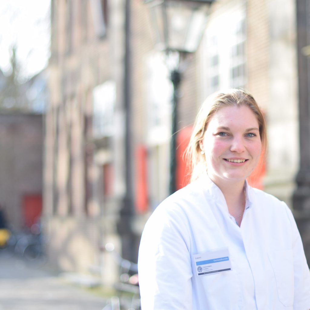 Een geneeskundestudent in doktersjas staat bij de Pieterskerk in Leiden tijdens de open dag van de universiteit.